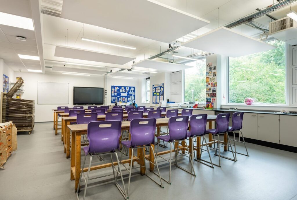 Klassrum med hängande rektangulära LED-ljuspaneeler som ger jämnt, bländfritt ljus och integreras med akustiska takskivor, en energieffektiv och stilren lösning från PROLJUS AB som förbättrar arbetsmiljön och är enkel att installera och underhålla