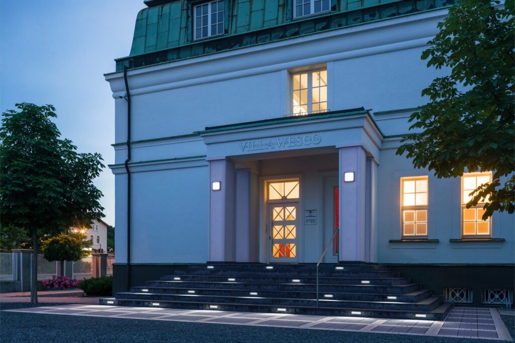 Entré i skymning upplyst av PROLJUS AB:s eleganta energieffektiva LED-armaturer med infälld stegbelysning i varje trappsteg och kvadratiska vägglampor som skapar trygghet och exklusiv atmosfär för villor, kontor och offentliga byggnader