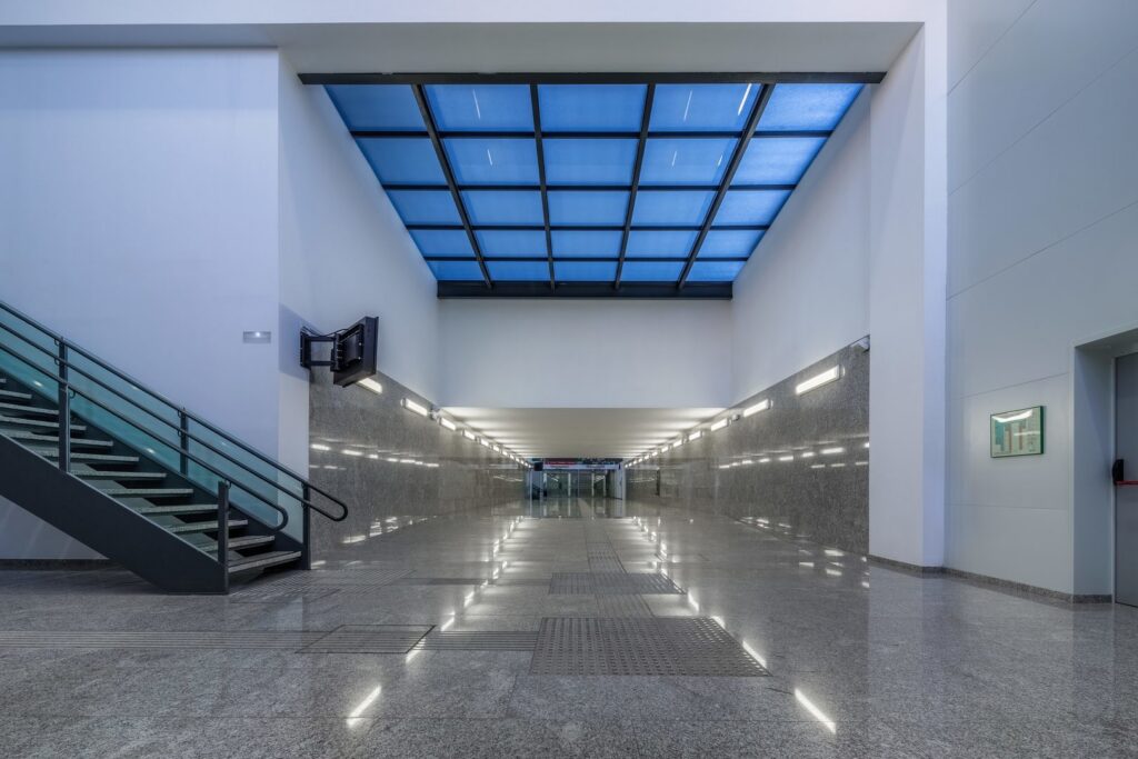 Modern offentlig korridor belyst av PROLJUS ABs linjära LED-armaturer monterade längs väggarna och i taket som ger jämn, bländfri och energieffektiv belysning med tydliga reflektioner i det polerade golvet idealiskt för tunnlar, entréer och kontor kontakta PROLJUS AB för offert