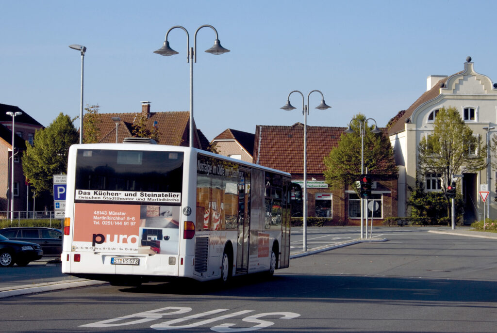 Foto av dubbelarmade gatlyktor i borstad metall på slanka stolpar över en stadsgata i dagsljus, välj PROLJUS AB för moderna och energieffektiva armaturer som förskönar stadsbilden