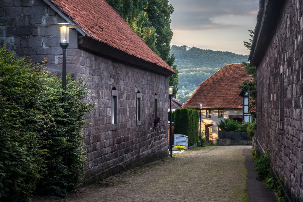 Kvällsgata med kullerstensgång och stenhus upplysta av PROLJUS ABs eleganta stolpar med klart glas och varm LED-belysning som framhäver murverkets textur och skapar trygg energieffektiv utebelysning perfekt för bostadsområden