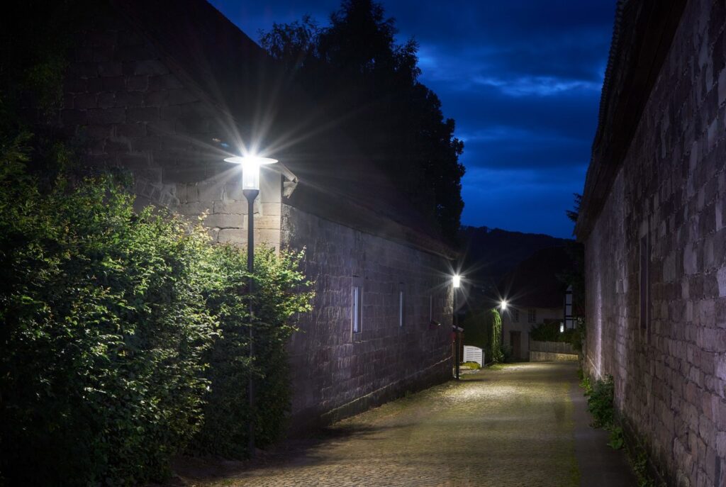 Kvällsbild av en kullerstensgränd upplyst av flera eleganta PROLJUS AB-armaturer som kastar ett klart, jämnt ljus över gångvägen och väggarna, energieffektiv och vädertålig konstruktion som skapar trygghet och ökar fastighetsvärdet