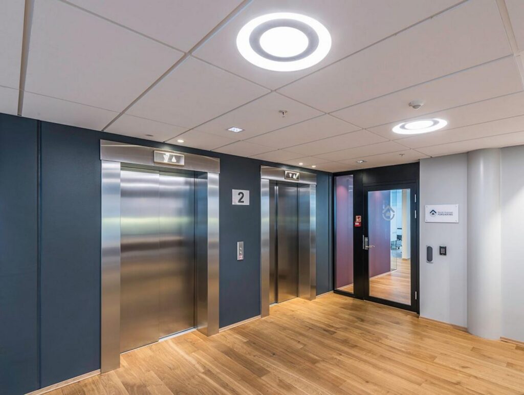 Kontorsentré med två hissar belysta av infällda ringformade LED-armaturer från PROLJUS AB, jämn bländfri och energieffektiv belysning som skapar en modern och inbjudande atmosfär