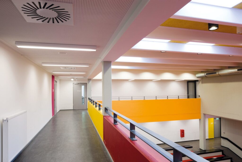 Ljus interiörkorridor med långa linjära infällda LED-armaturer, nedsänkta spotlights och takljus som skapar jämnt bländfritt arbetsljus — energieffektiva belysningslösningar från PROLJUS AB