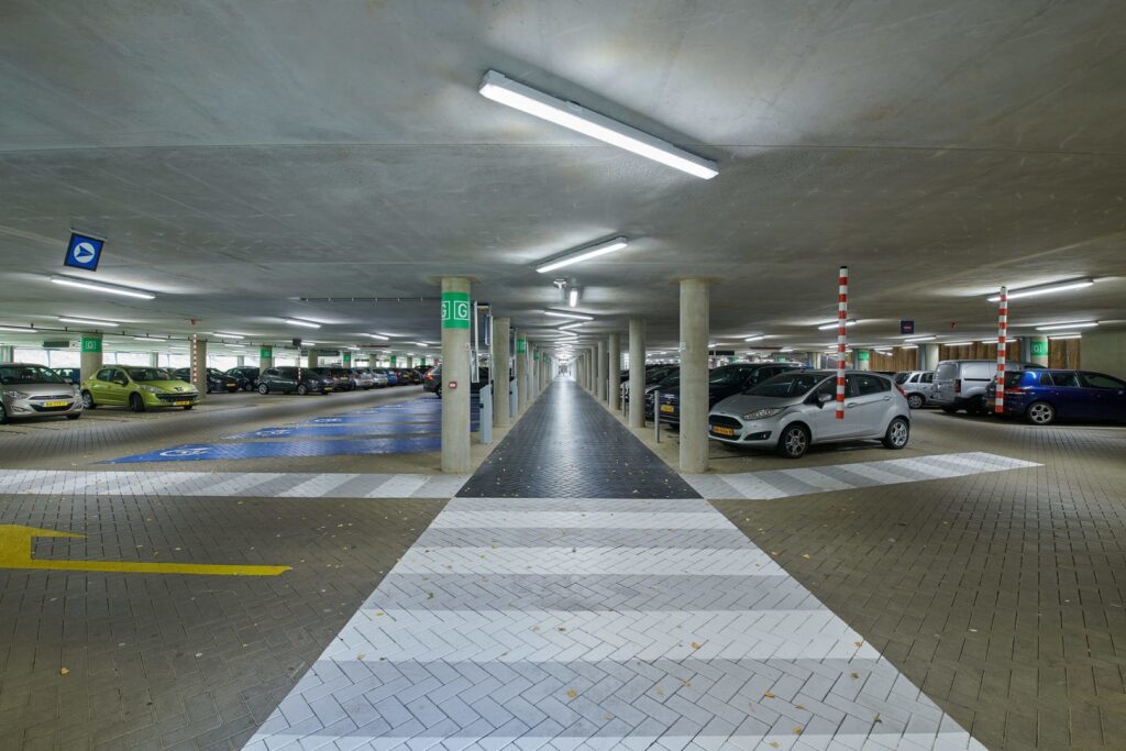 Takmonterade linjära LED-armaturer från PROLJUS AB sprider kallvitt, jämnt och bländfritt ljus genom ett underjordiskt parkeringsgarage, markerar gångstråk och parkeringsrader, ökar tryggheten med låg energiförbrukning och lång livslängd