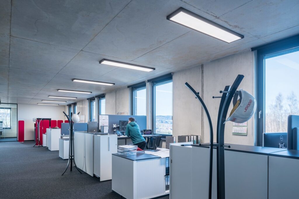 Energieffektiva rektangulära LED‑takarmaturer i slimmat, modernt utförande monterade i betongtak ger jämnt och bländfritt arbetsljus som förbättrar kontorsmiljön och minskar energikostnaderna, perfekt för öppna kontorslandskap från PROLJUS AB