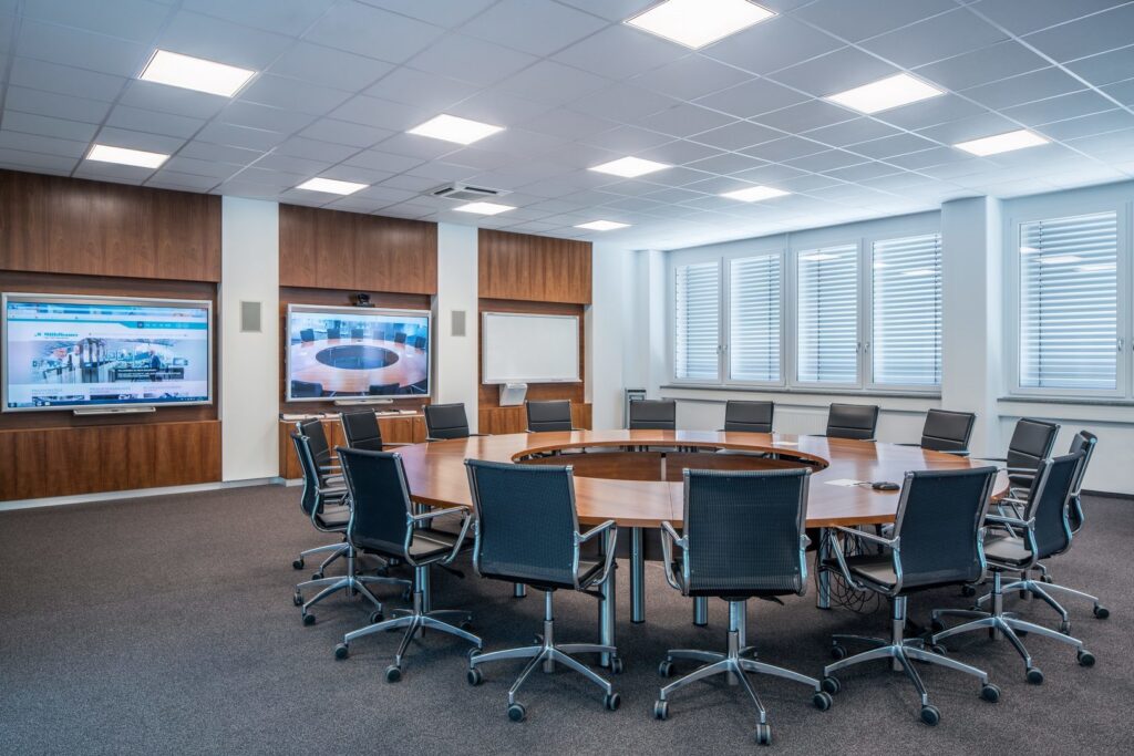 Konferensrum med runt träbord upplyst av jämnt fördelade infällda LED-armaturer i undertak som ger klart, bländfritt arbetsljus, energieffektiva och högkvalitativa belysningslösningar från PROLJUS AB