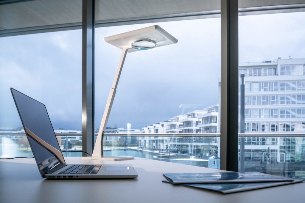 Stilren vit LED-armatur från PROLJUS AB på kontorsbord med slank ergonomisk arm och riktat bländfritt arbetsljus, energieffektiv och perfekt för professionella arbetsmiljöer