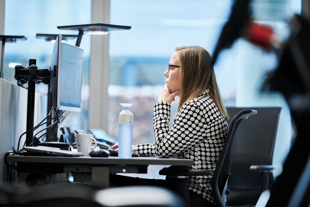 Kontorsmiljö med PROLJUS AB:s moderna LED-armaturer monterade ovanför arbetsstationer, riktat bländfritt ljus som ger jämn, energieffektiv belysning och förbättrad arbetskomfort