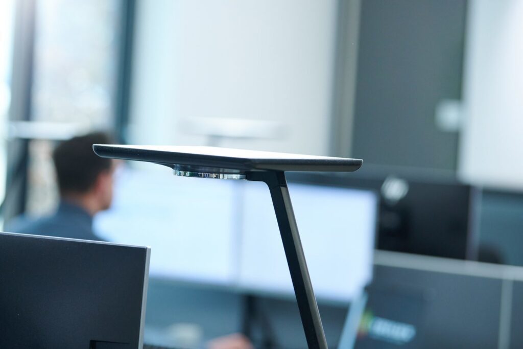 PROLJUS AB:s slimmade moderna LED-armatur med tunn snedställd arm och platt ljuspanel i kontorsmiljö, elegant design för riktat arbetsljus och energieffektiv belysning som lyfter arbetsplatsen