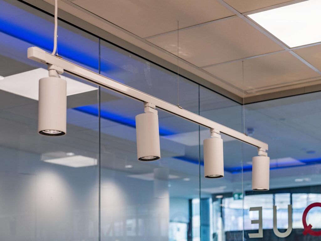 Fyra vita cylindriska LED-armaturer monterade på en vit skena i stilren takhängd installation som exemplifierar PROLJUS ABs energieffektiva och högkvalitativa belysningslösningar för butik och kontor