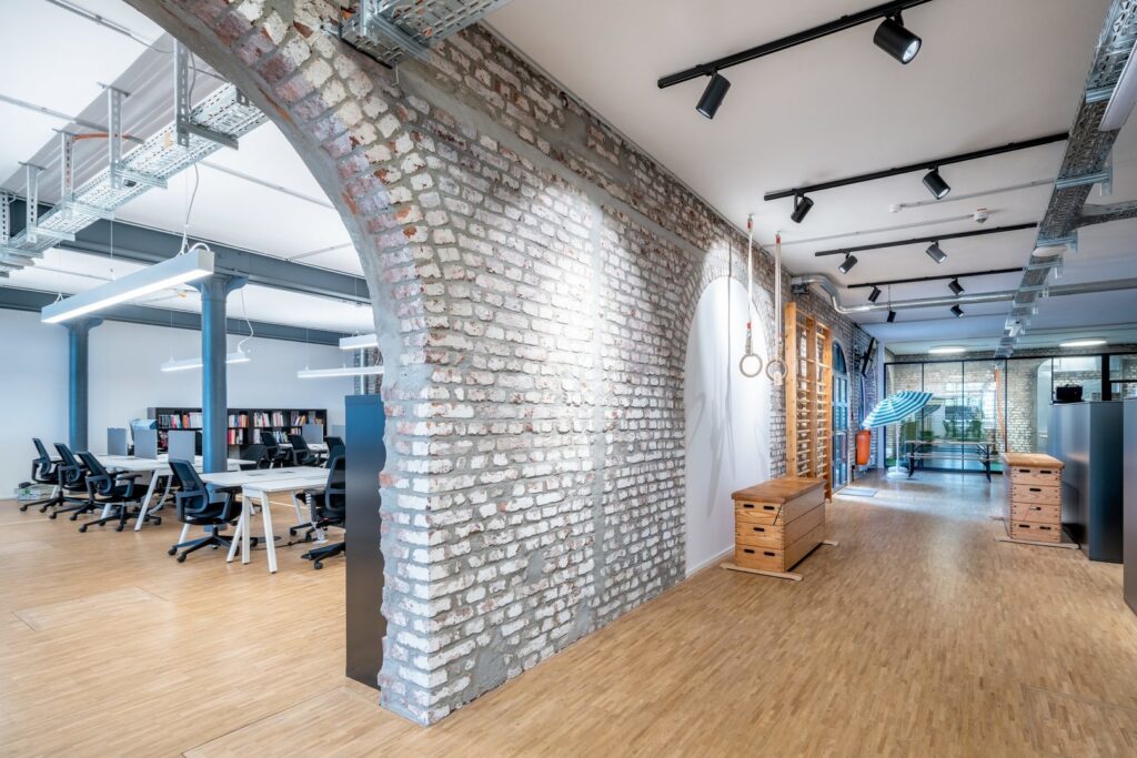 Öppet kontor med svarta skensystem och riktbara spotlights, upphängda linjära LED-armaturer över skrivbord, infällda taklampor och synliga kabelstegar som skapar jämn, energieffektiv arbetsbelysning och visar PROLJUS ABs moderna belysningslösningar