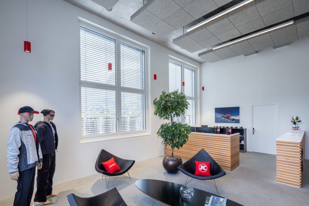 Reception med PROLJUS AB:s moderna armaturer, inklusive röda cylinderpendlar och långa takmonterade LED-linjer integrerade i akustikplattor som ger jämnt och energieffektivt ljus samt framhäver inredningen, perfekt för kontor och butik, kontakta PROLJUS AB