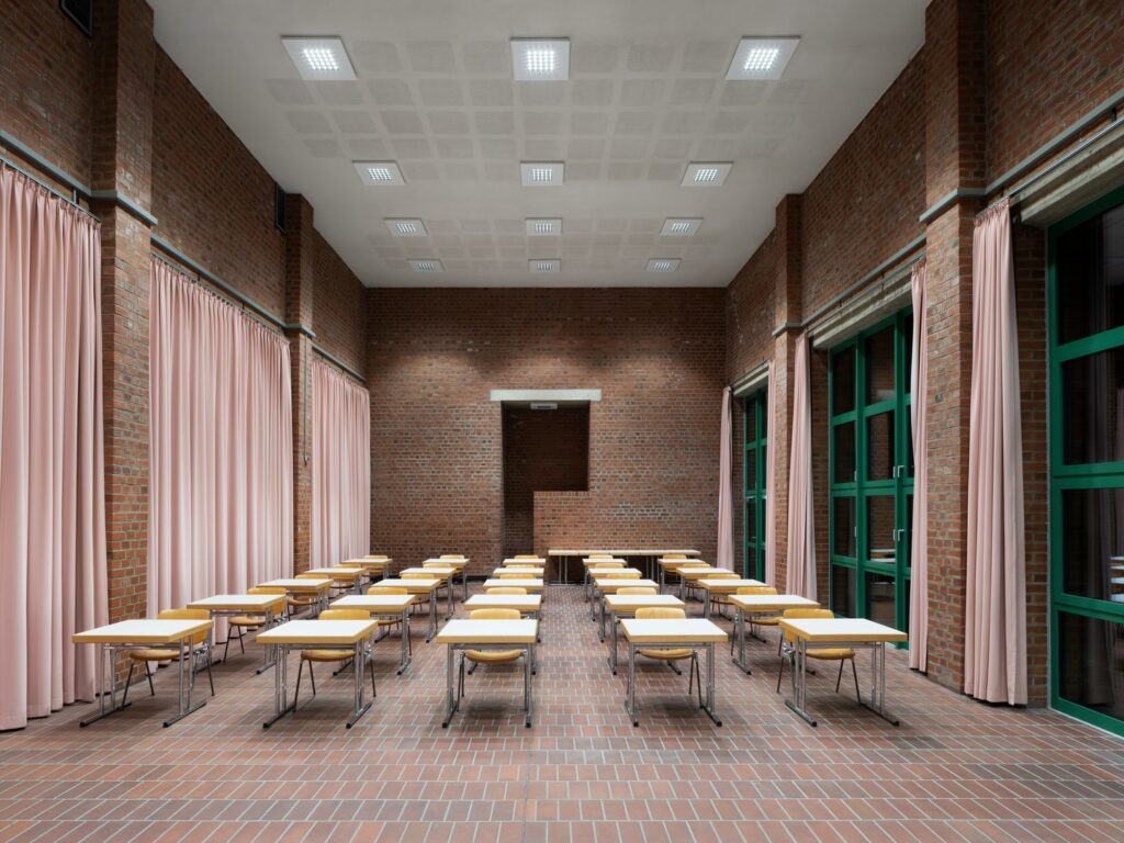 Hög tegelhall belyst av en symmetrisk matris av infällda kvadratiska LED-armaturer som ger jämnt, bländfritt och energieffektivt ljus perfekt för skolor och konferenser kontakta PROLJUS AB för moderna belysningslösningar och offert