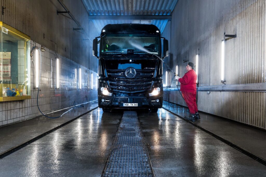 Fordonsvätt upplyst av väggmonterade PROLJUS LED-armaturer, jämnt och bländfritt ljus längs båda sidor reflekteras i våta golv och visar armaturernas tålighet och fuktskydd, idealiskt för verkstäder och tvätthallar, PROLJUS AB levererar energieffektiva, lättmonterade och professionella belysningslösningar