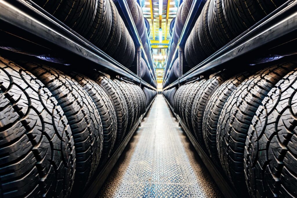 Industriella LED-armaturer från PROLJUS AB lyser klart och jämnt över en lång lagergång med rader av bildäck, framhäver däckmönster och visar energieffektiv och säker belysning för lagerlokaler