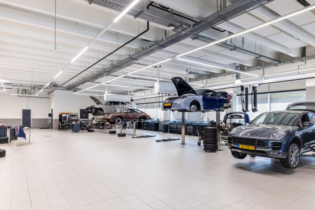 Stort modernt bilverkstad upplyst av långa linjära LED-armaturer i taket som ger jämnt, skuggfritt och energieffektivt arbetsljus, perfekt för industrilokaler och levererat av PROLJUS AB