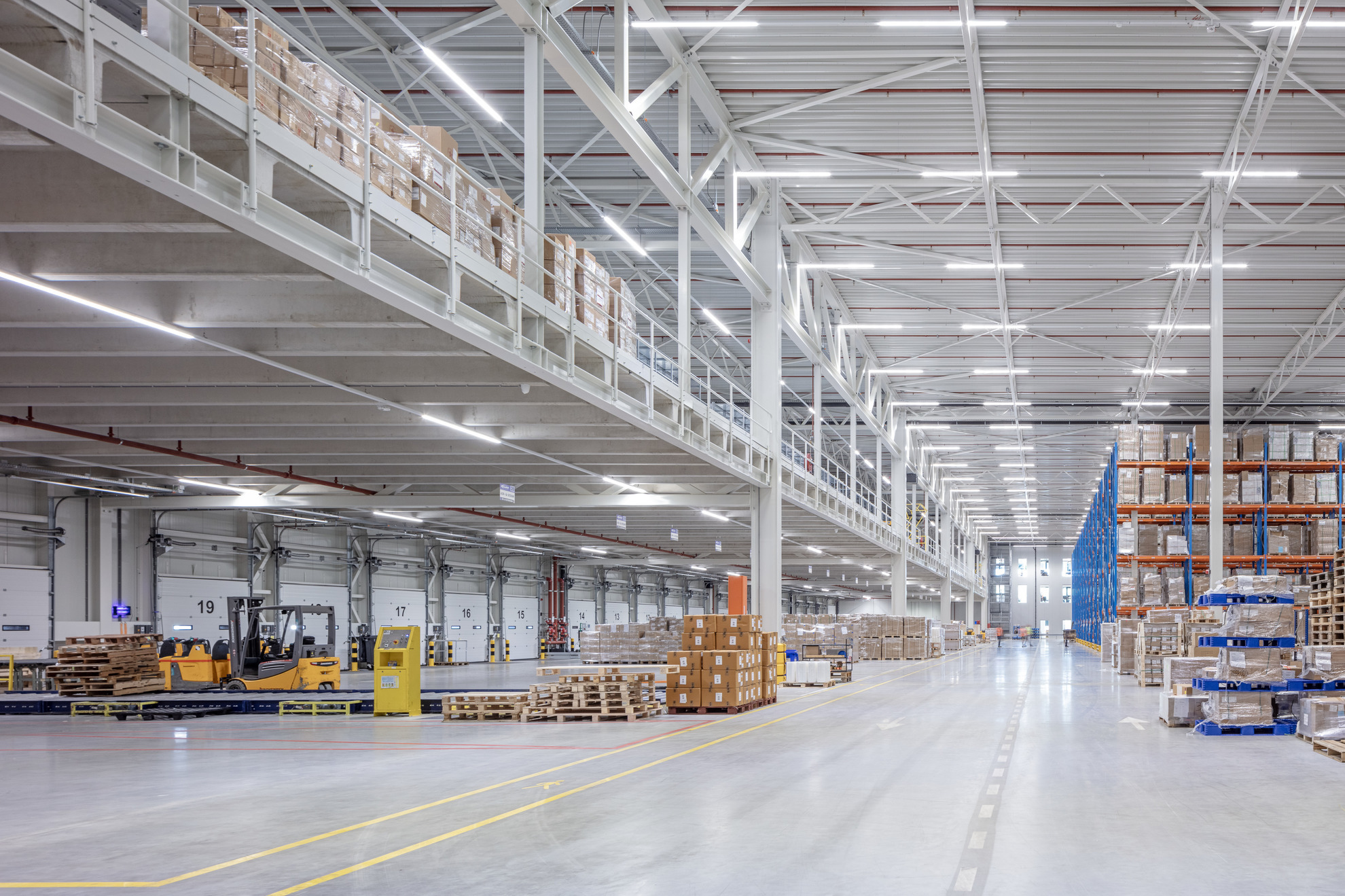 Modernt logistiklager med pallställ, lastportar och truckar – effektivt distributionscenter för e‑handel.