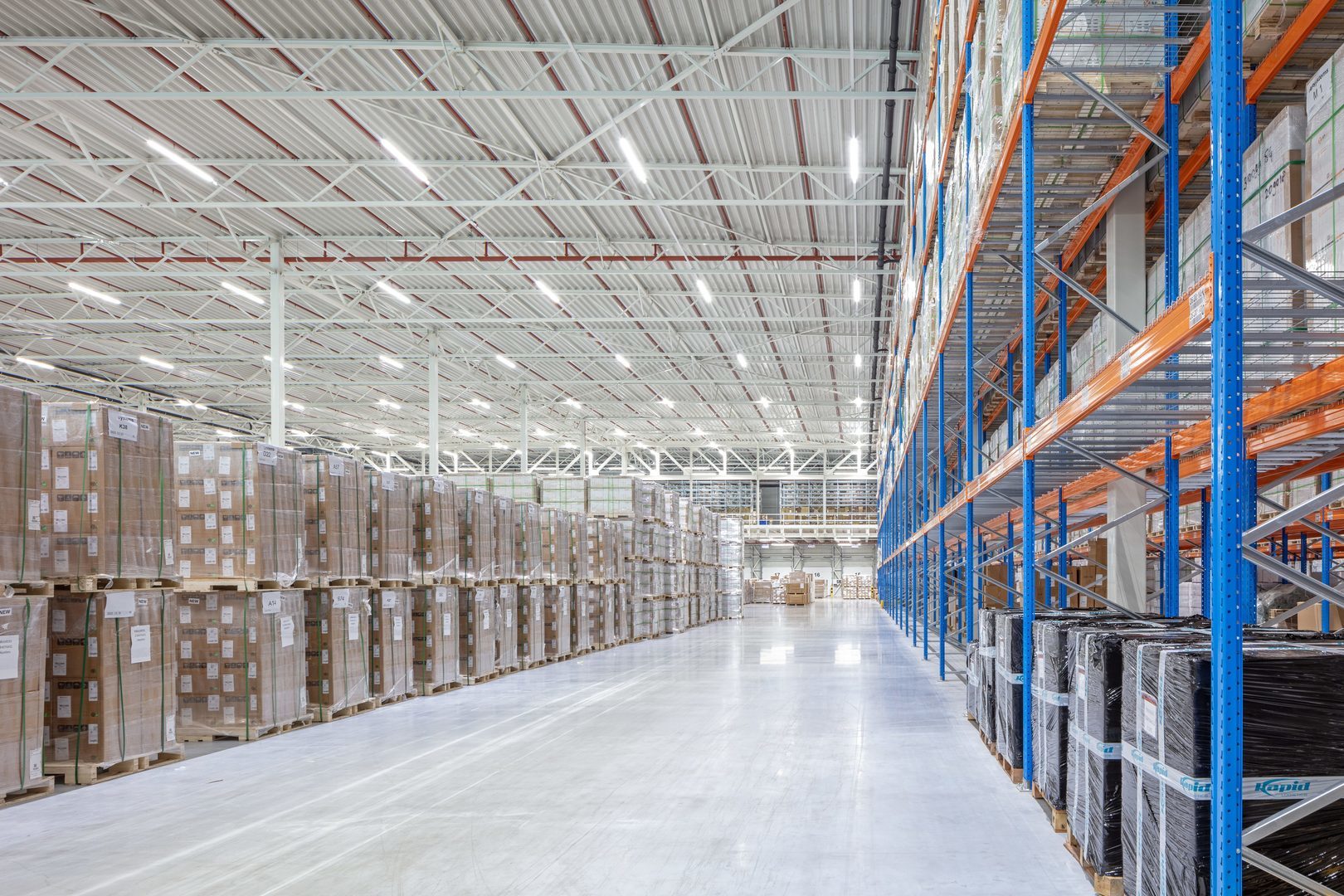 Ljust, rymligt lager upplyst av långa rader energieffektiva LED‑luminärer i taket, PROLJUS AB:s högpresterande armaturer ger jämn, bländfri belysning som ökar säkerhet och produktivitet samtidigt som de minskar energikostnader