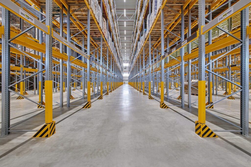 Lång symmetrisk lagergång belyst av linjära energieffektiva LED-armaturer i taket som ger jämnt bländfritt arbetsljus och visar PROLJUS ABs professionella belysningslösningar