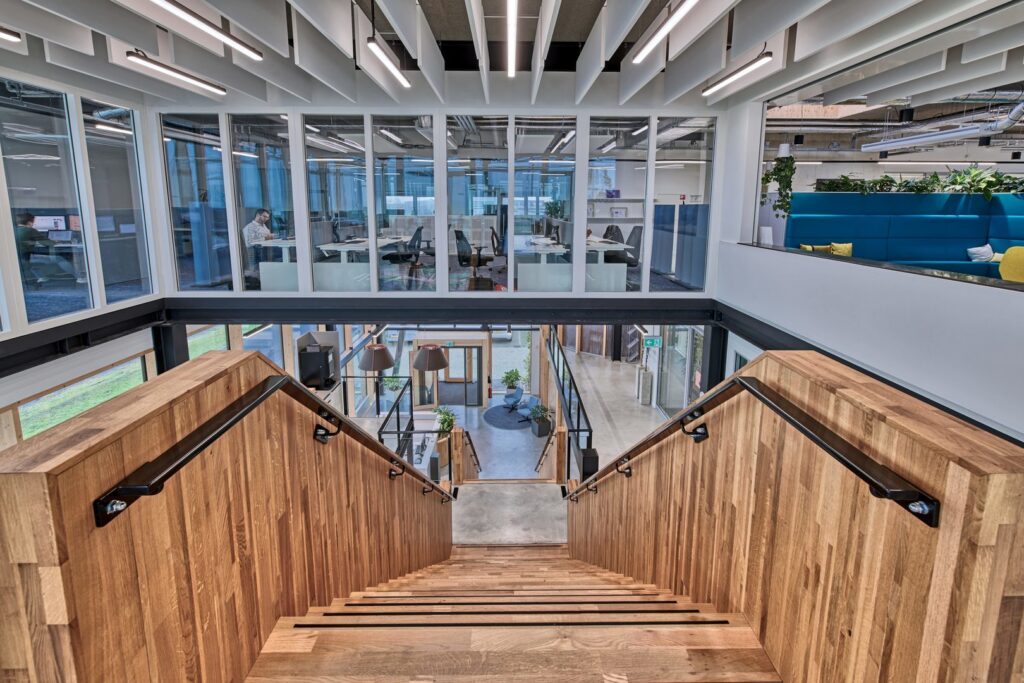 Öppet kontor med moderna linjära LED-armaturer monterade mellan vita akustiska takbafflar som sprider jämnt, bländfritt och energieffektivt ljus, ett flaggskeppsprojekt för PROLJUS AB