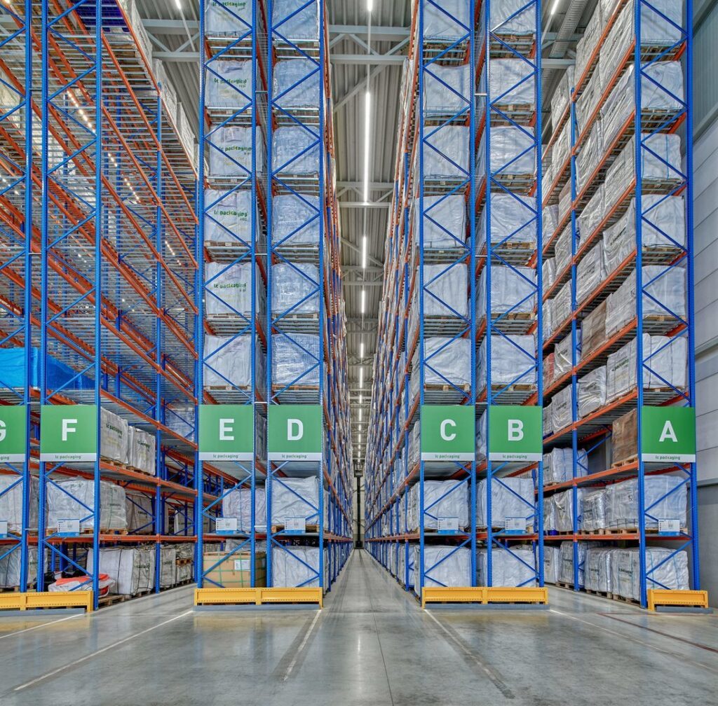 Takmonterade LED-armaturer från PROLJUS AB i ett stort höglager som skapar kraftfullt, jämnt och energieffektivt arbetsljus längs en lång mittgång, en kostnadseffektiv lösning för förbättrad säkerhet och produktivitet