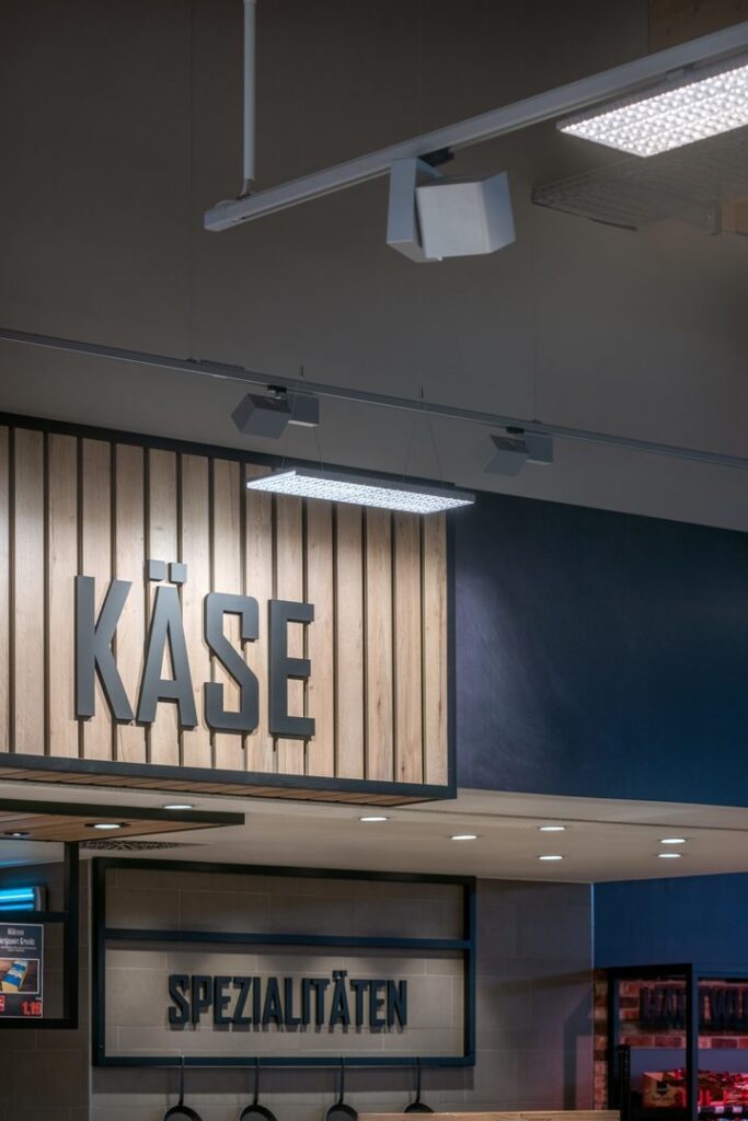 Spårmonterade spotlights och hängande rektangulär LED-panel ger jämn, energieffektiv belysning som framhäver butiksskyltar och varor, perfekt för att öka försäljningen med PROLJUS AB