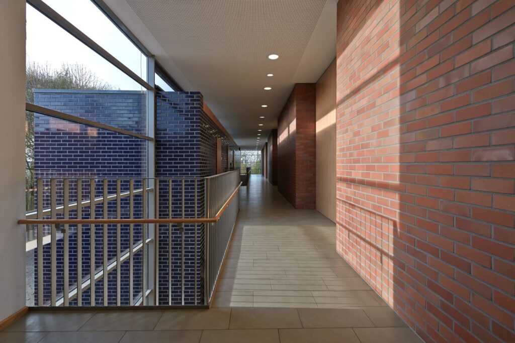 Korridor belyst av en rad infällda LED-downlights från PROLJUS AB som ger jämnt varmt och energieffektivt ljus längs tegelväggar och räcke