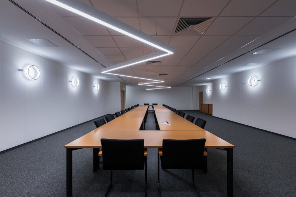 Konferensrum upplyst av PROLJUS ABs Z‑formade LED‑taklist och cirkulära väggarmaturer som ger jämnt, energieffektivt arbetsljus och stilren sidobelysning perfekt för professionella mötesrum, kontakta PROLJUS AB för skräddarsydda belysningslösningar