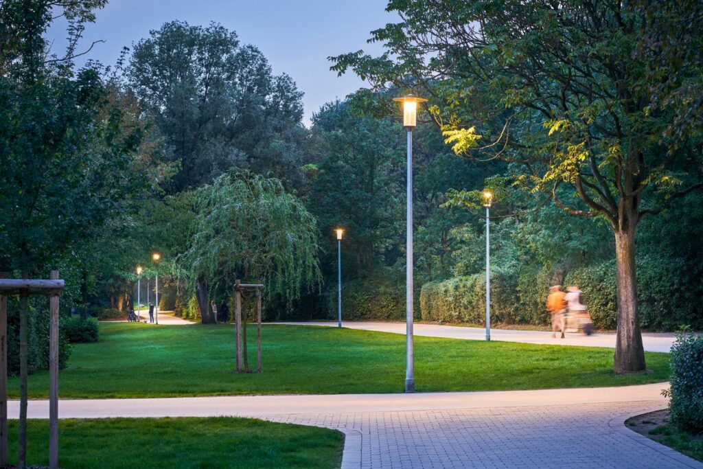 Kvällsbild av en parkväg upplyst av en rad moderna PROLJUS AB parkarmaturer som ger varm och jämn ljusspridning över gång‑ och cykelväg samt framhäver grönskan för en trygg och energieffektiv utemiljö