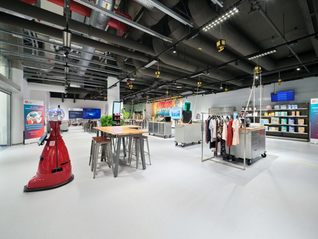 Butiksshowroom med synligt industriellt undertak där PROLJUS AB:s flexibla LED-skenor, riktade spotlights och hängande linjära armaturer skapar jämn, energieffektiv och säljdrivande belysning för produkter och arbetsytor — kontakta PROLJUS AB för skräddarsydda lösningar
