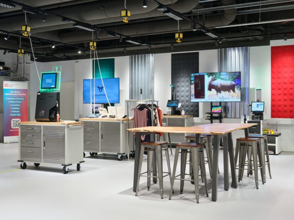 Modern butiksmiljö belyst av PROLJUS AB:s svarta skensystem med justerbara spotlights, långa energieffektiva LED-paneler och hängande gula arbetslampor på spiralupphängning som ger riktat, stämningsfullt ljus och inspirerar till köp hos PROLJUS AB