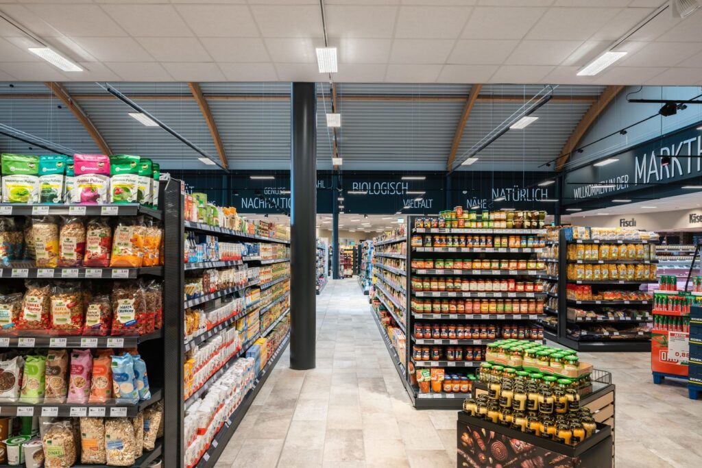 Interiör av livsmedelsbutik upplyst av moderna, energieffektiva PROLJUS LED-armaturer och linjära pendlar i taket som ger jämnt, klart ljus och framhäver hyllornas varor, kontakta PROLJUS AB för butikslösningar och offert