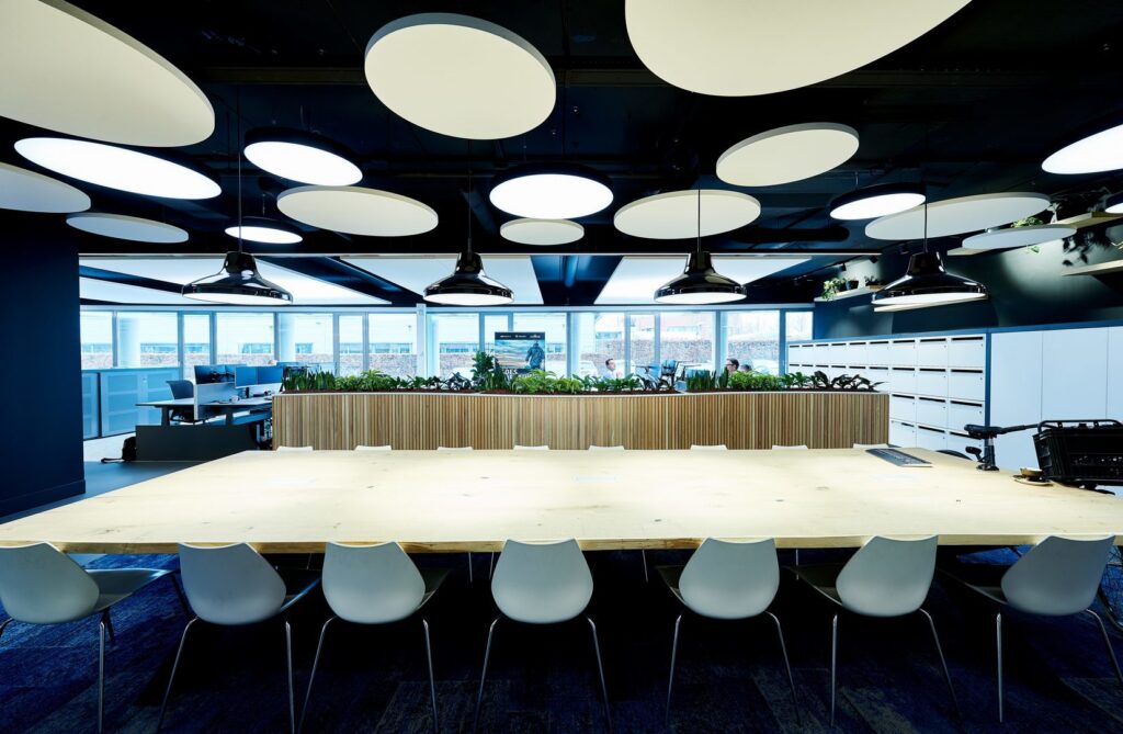 Stilren kontorsbelysning med stora runda takpaneler och svarta hängande pendellampor som sprider jämnt dagsljusliknande LED‑ljus, levererat av PROLJUS AB för effektiv och modern arbetsplatsbelysning