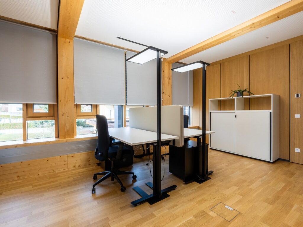 Svarta fristående LED-armaturer från PROLJUS AB med tunna rektangulära paneler som ger jämnt, bländfritt ljus över skrivbord i öppet kontor, energieffektiva och höjdjusterbara för ökad produktivitet