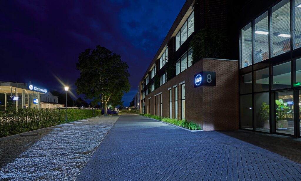 Nattbild av kontorsfasad och gångväg upplyst av energieffektiva fasadarmaturer och pollare från PROLJUS AB, jämn ljusfördelning som framhäver arkitektur, ökar trygghet och sparar energi för kommersiella fastigheter