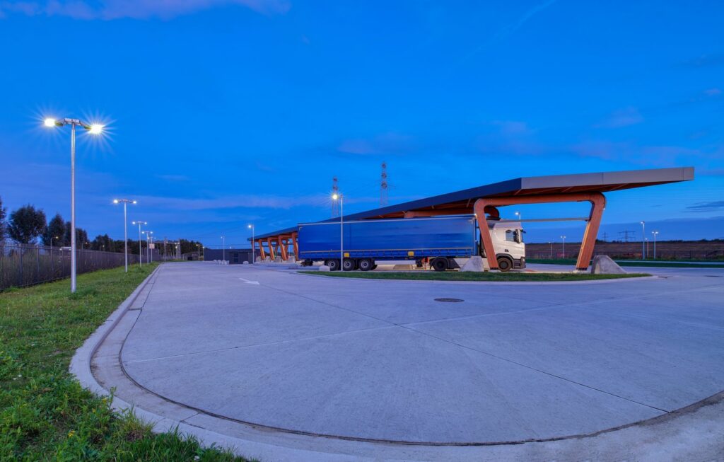 Kvällsbild av en logistikplats där PROLJUS AB:s energieffektiva LED-armaturer på stolpar och under tak ger klart och jämnt ljus över lastbryggor, förbättrar säkerhet och synlighet samt minskar energikostnader och lyfter modern industridesign