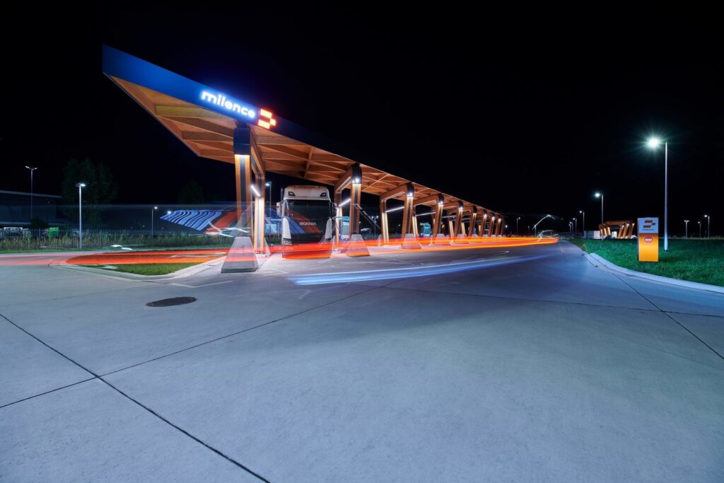 Nattbild av en modern lastbilshållplats upplyst av PROLJUS ABs LED-armaturer monterade under ett långsträckt trätak och som gatlyktor, ger jämnt energieffektivt vitt ljus som förbättrar säkerhet och synlighet och visar PROLJUS ABs pålitliga belysningslösningar