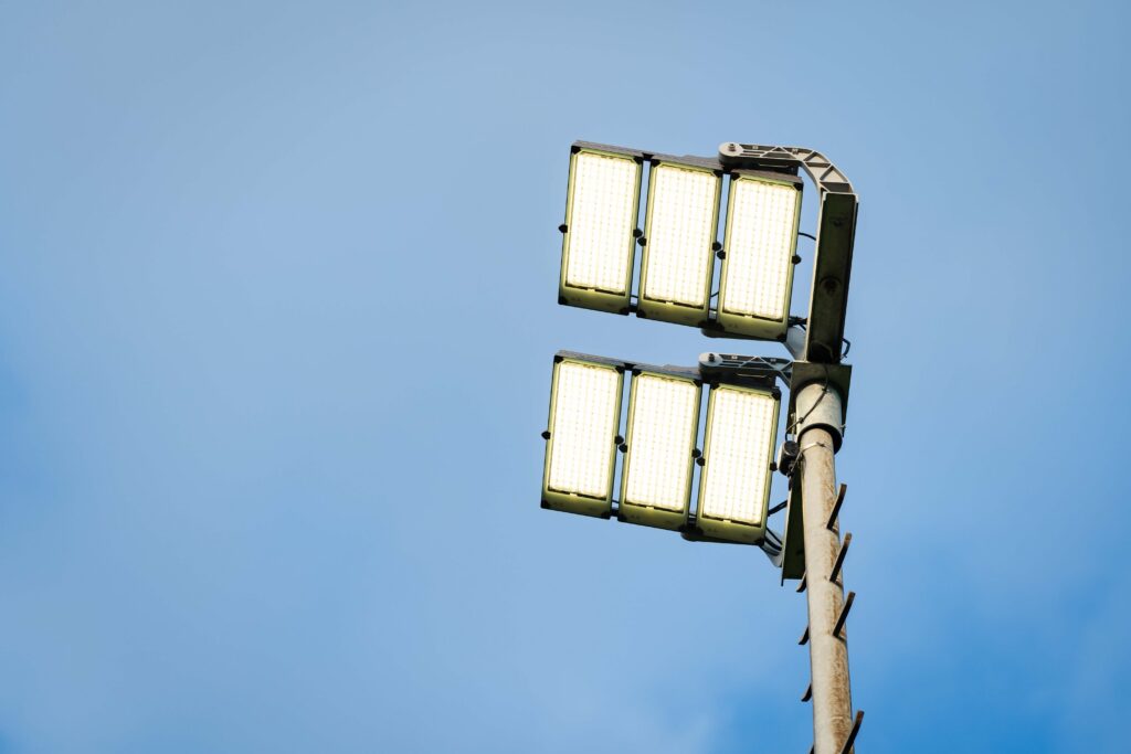 Högpresterande energieffektiva LED-strålkastare monterade i par på en robust mast mot klarblå himmel, idealiska för sportarenor och industrimiljöer från PROLJUS AB