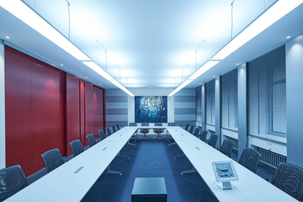 Konferensrum upplyst av PROLJUS ABs slanka pendlande LED-armaturer i taket som ger jämnt kallvitt ljus över långa bord och skapar en energieffektiv, professionell atmosfär