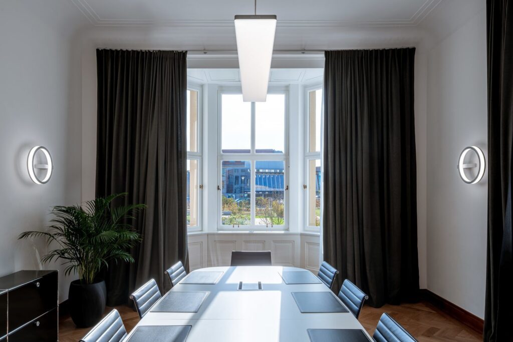 Modernt mötesrum med rektangulär LED-pendel som ger jämnt arbetsljus och två ringformade väggarmaturer som skapar accentbelysning, energieffektiva och stilrena armaturer perfekta för kontor från PROLJUS AB