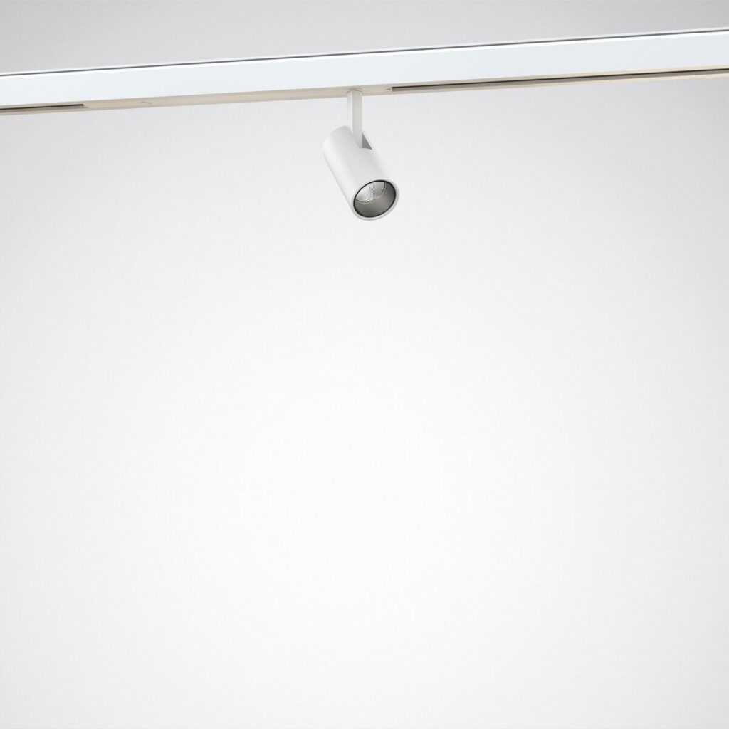 Vitt cylindriskt LED-spårarmatur från PROLJUS AB monterat i takets skena, justerbar och högkvalitativ med koncentrerat, energieffektivt ljus perfekt för butiksexponering och gallerier