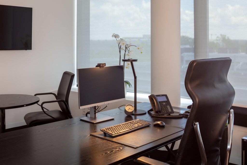 Stilrent kontorsskrivbord med PROLJUS ABs moderna, energieffektiva bordsarmaturer, en slimmad svart arbetslampa med justerbar arm och rund bas samt skärmbelysning som ger jämnt riktat ljus för produktiva arbetsmiljöer och premiumdesign