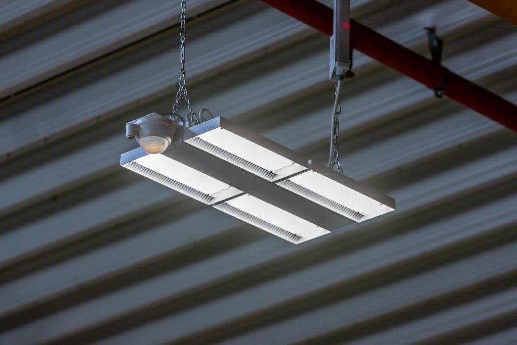 Hängande LED-armatur i vit metall med fyra ljusrampaneler och kedjeupphängning, hög ljuseffektivitet och jämn ljusspridning perfekt för lager och industrilokaler från PROLJUS AB
