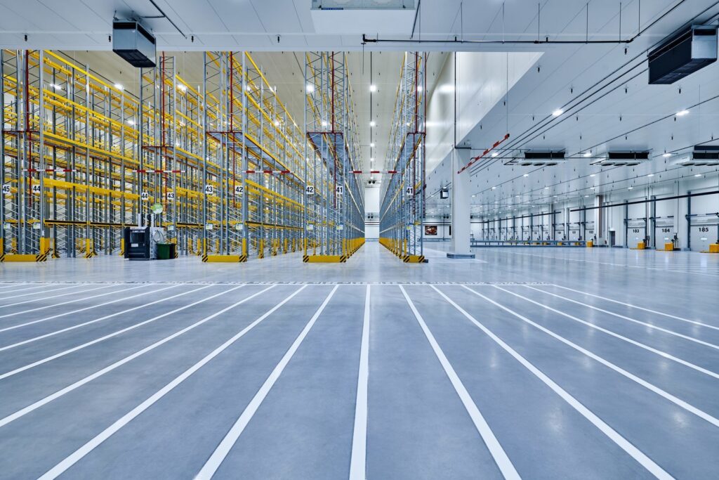 Stort modernt lager lyses upp av rader av energieffektiva takarmaturer som ger jämnt, starkt och bländfritt arbetsljus perfekt för industriella miljöer från PROLJUS AB