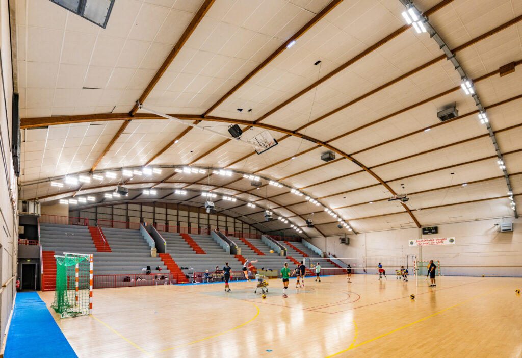 Sporthall med radvis monterade energieffektiva LED-armaturer i bågtak som ger jämnt, bländfritt ljus över spelplan och läktare, optimerade för idrottsmiljöer från PROLJUS AB