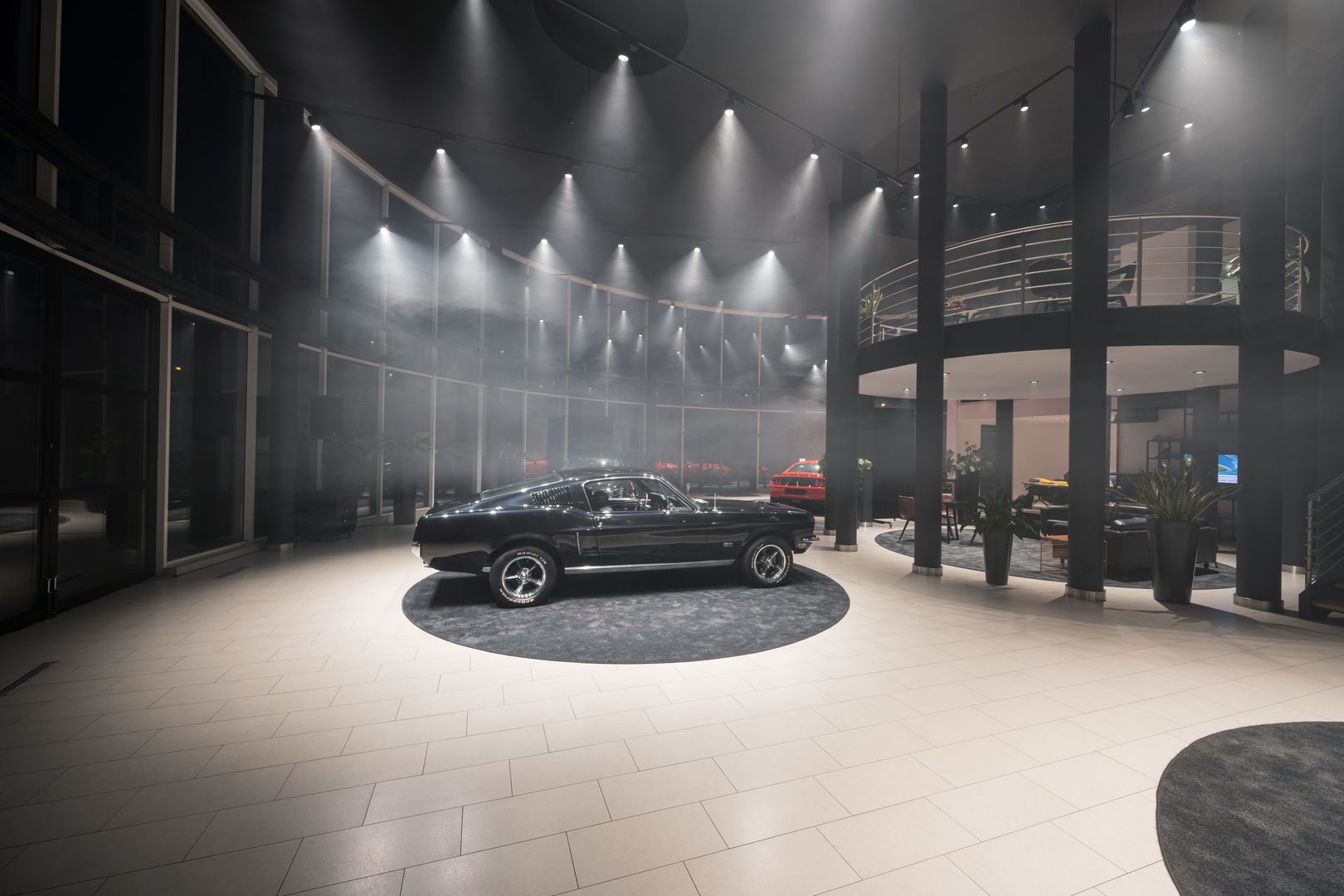 Showroom med cirkulär scen där PROLJUS ABs energieffektiva LED-skenspottar och riktade downlights skickligt framhäver en klassisk bil, skapar dramatisk rökfylld strålkastning, jämn golvbelysning och en inbjudande, säljdrivande atmosfär