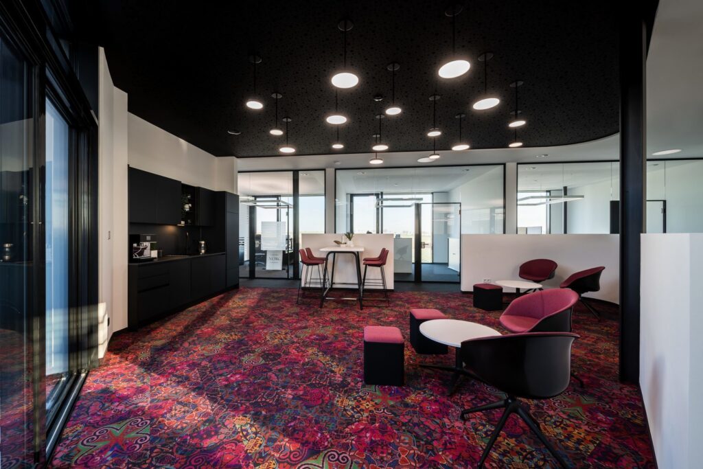 Stilfull kaskad av runda LED-pendellampor i varierande höjder mot ett svart perforerat tak som sprider jämnt, varmt arbetsljus i en modern kontorsmiljö, en energieffektiv och designad belysningslösning från PROLJUS AB