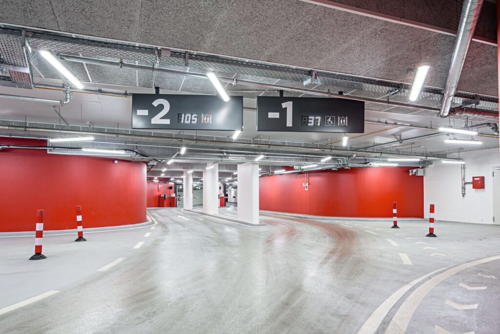 Ett underjordiskt parkeringsgarage med hängande energieffektiva LED-armaturer från PROLJUS AB som ger jämnt och bländfritt ljus över rampytorna, med modern industriell design och robust konstruktion idealiska för säker och kostnadseffektiv garagebelysning