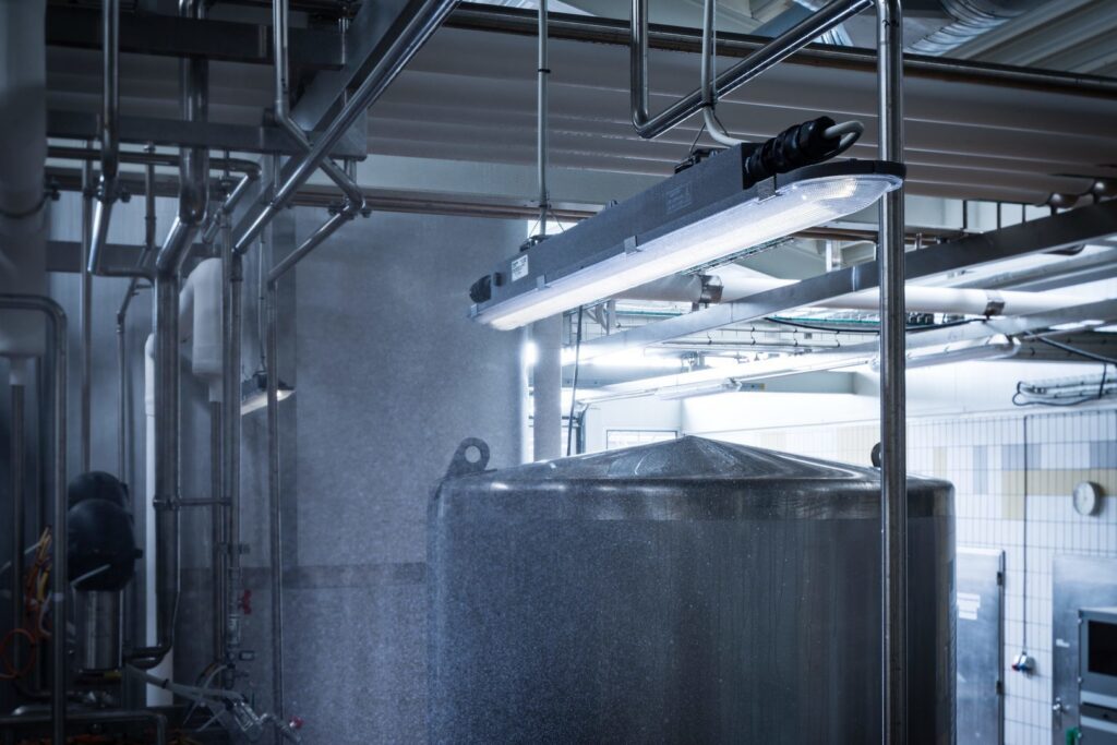 Upphängd PROLJUS AB LED-armatur i industrimiljö som ger starkt och jämnt stänksäkert ljus över rostfri tank, energieffektiv och robust lösning för produktionslokaler
